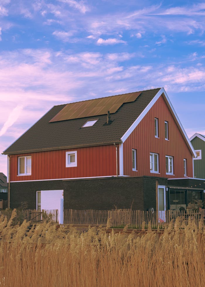 Charming traditional farmhouse with solar panels under a blue sky in Arnhem, Netherlands.